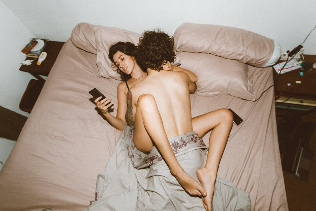 Couple having sex with woman distracted by phone